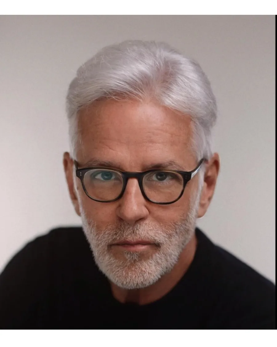 Headshot of John Amedro, silver-haired character actor in glasses